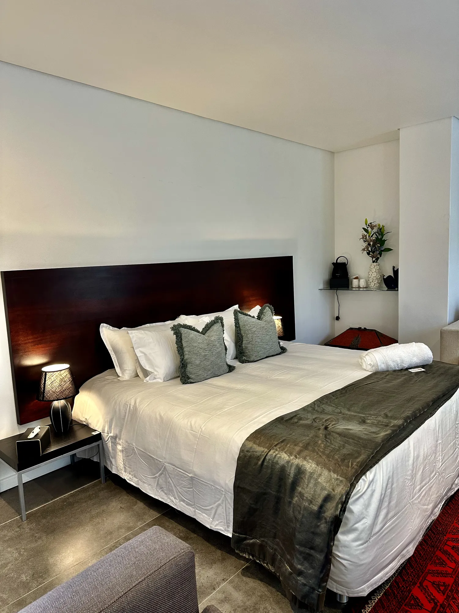 A Casa Dias bedroom with a dark timber headboard and sitting shelf