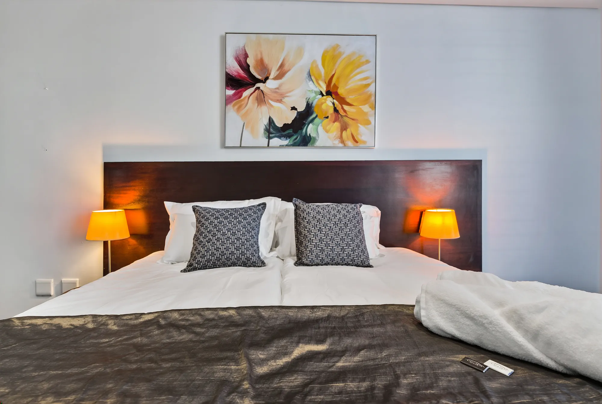 A made bed with floral artwork above the headboard at Casa Dias