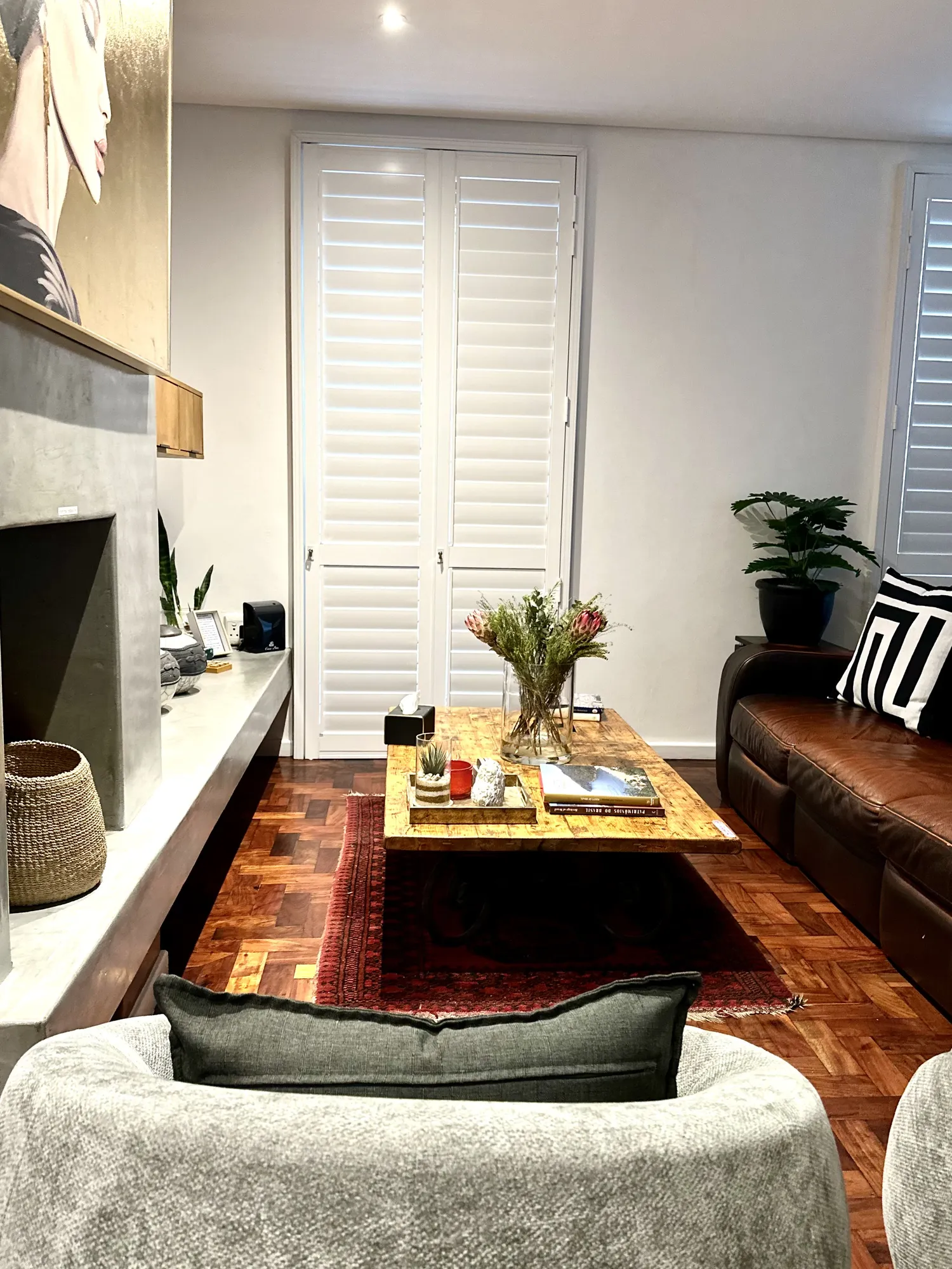 The living room at Casa Dias with a fireplace, leather sofa, and plantation shutters