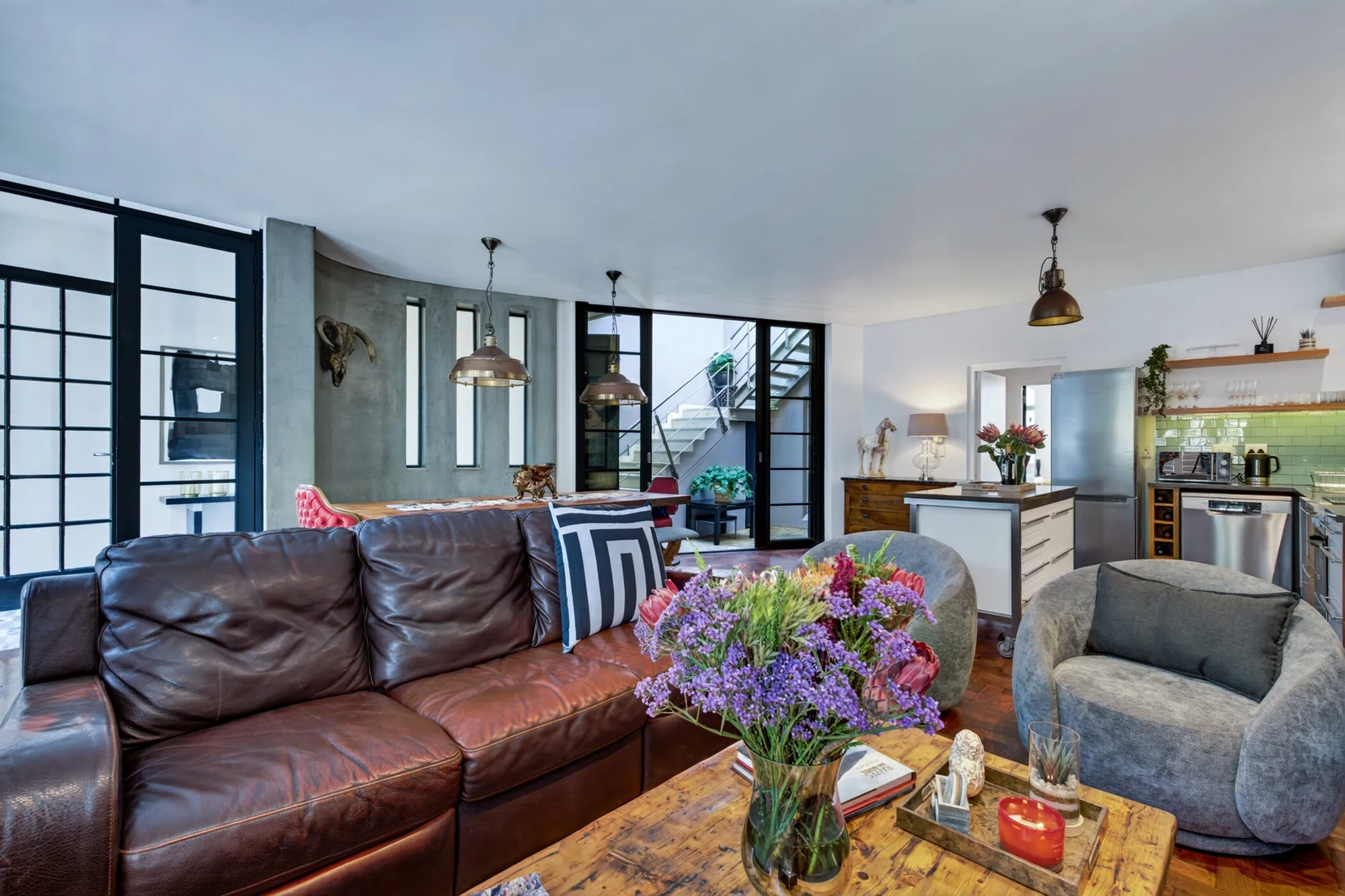 The Casa Dias living room with a leather sofa, timber coffee table, and open kitchen beyond